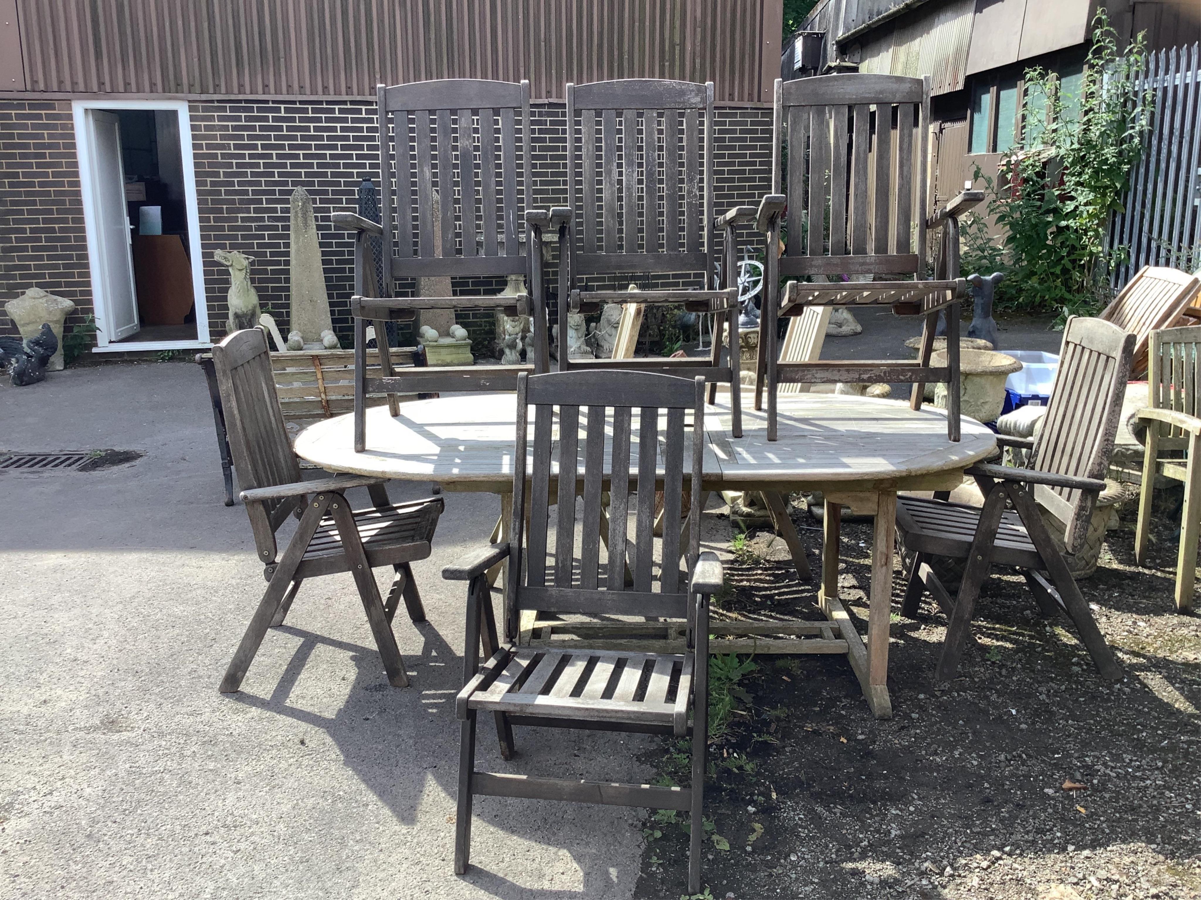 A weathered teak extending garden table, width 210cm extended, depth 120cm, height 75cm, together with six (four plus two) stained teak garden armchairs. Condition - fair